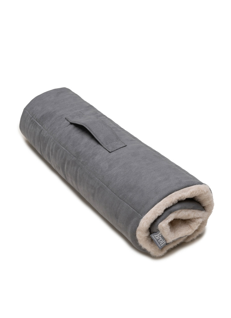 Roll bed portátil para perro, color gris oscuro por fuera y color beige claro en el interior. De suave tacto por el pelo reciclado que aporta calidez y ligereza. Ideal para aventuras junto a tu perro.